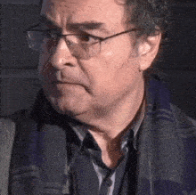 a man wearing glasses and a scarf is looking at the camera