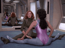 a woman in a purple leotard sits next to another woman
