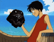 a boy in a red tank top is holding a black object