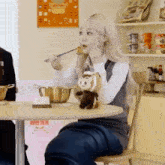 a girl is sitting at a table eating food with chopsticks .