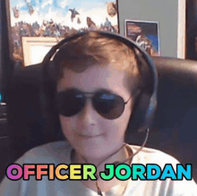 a young boy wearing headphones and sunglasses is sitting in a chair and says officer jordan .