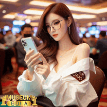 a woman wearing glasses is looking at her phone with a museum bola logo in the background