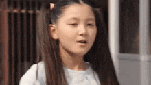 a young girl with pigtails is standing in front of a door .