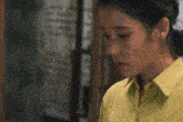a woman in a yellow shirt is looking down with her eyes closed