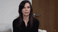 a woman in a black shirt is sitting in front of a door that says ad on it