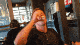 a man in a black shirt is drinking from a cup in front of a sign that says " happy birthday "