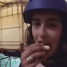 a woman wearing a blue helmet eating a piece of food