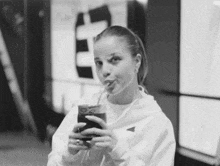 a black and white photo of a woman drinking from a cup