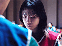 a woman with her eyes closed is wearing a red vest