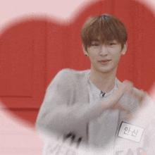 a man with a name tag that says ' 안신 ' on it is making a heart shape with his hands