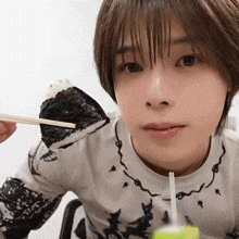 a woman eating a piece of food with chopsticks and a bottle of water in front of her