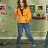 a woman in a yellow jacket and blue jeans is dancing in a living room .