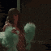 taylor swift is wearing a green fur coat and a gold dress while sitting on a chair .