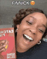 a woman is smiling while holding a book that says finnick