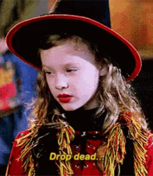 a girl in a witch costume says drop dead in yellow letters