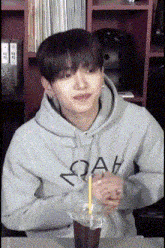 a man in a hoodie is sitting at a table with a cup of coffee .
