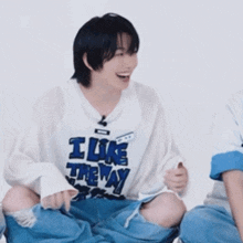 a young man wearing a white shirt that says i like the way is laughing .