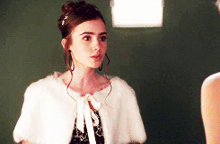 a woman wearing a white fur cape and earrings stands next to another woman