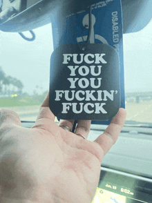 someone is holding a air freshener that says fuck you you fuckin ' fuck