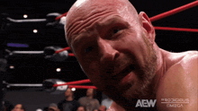 a bald man with a beard is in a wrestling ring that says aew on the bottom