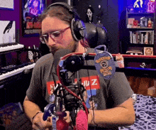 a man wearing headphones is sitting in front of a microphone and a keyboard .