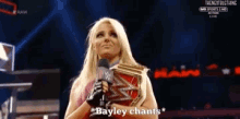 a female wrestler is holding a wrestling trophy and says bayley chants