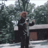a man in a cowboy hat holds a large fish