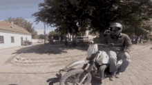 a man wearing a helmet is riding a dirt bike on a brick road