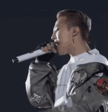 a man is singing into a microphone while wearing a white shirt and a gray jacket .