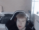a young man wearing headphones is sitting in a gaming chair .