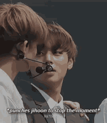 two young men are standing next to each other and one of them is wearing a microphone in his mouth .