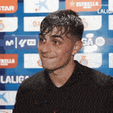a man in a black shirt is smiling in front of a sign that says estrella