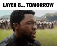 a man with a beard is standing in front of a crowd of people and says `` layer 8 tomorrow '' .