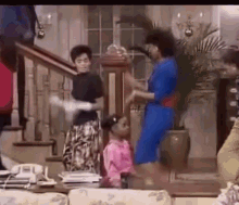 a group of people are dancing in a living room with stairs in the background .