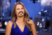 a woman in a blue dress with a fake beard and mustache is smiling .