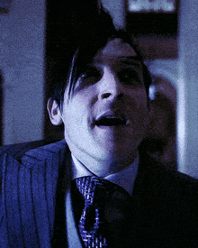a man in a suit and tie is looking at the camera with his mouth open