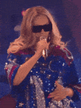 a woman singing into a microphone wearing sunglasses