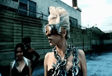 a woman wearing a chain around her neck is standing in front of a building .