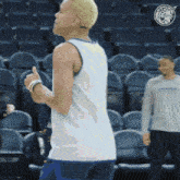 a man giving a thumbs up in a stadium with a basketball logo in the background