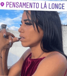 a woman is smoking a cigarette while wearing a red dress and a necklace .