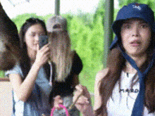 two women are standing next to each other and one is wearing a hat and tie .
