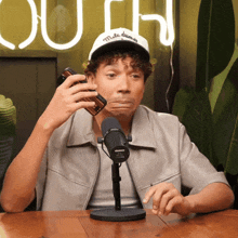 a man sitting in front of a microphone wearing a white hat that says " male dreamer "
