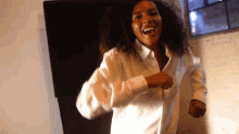 a woman in a white shirt is dancing in a room
