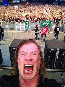 a man taking a selfie in front of a crowd with the letter e on the fence