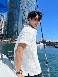 a man in a white shirt is standing on a boat in the water