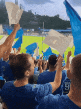 a group of people waving blue and white flags in a stadium