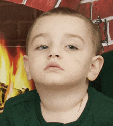 a young boy wearing a green shirt is looking at the camera