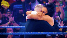 a woman is hugging a man in a wrestling ring with the words index-wwe-gifs on the bottom right