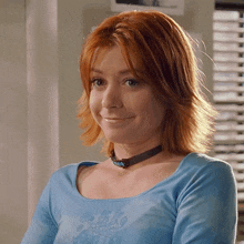 a woman with red hair wearing a blue shirt and a choker
