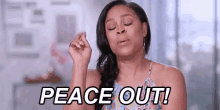 a woman is making a peace sign with her eyes closed and the words peace out .